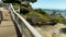 panning footage along the footpath at Dana Point Bluff Top Trail with hotels, blue ocean water and boats and yachts docked