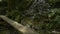 Panning shot of beautiful scenery of water stream flowing from the cascade over the rocks with wooden bridge.