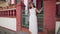 Panning shot of cheerful tourist standing at red and white fence in ancient town on Cyprus looking around. Smiling