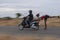 Panning shot  of a man driving scooter and aboy holding and skating behind