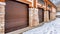 Pano Building exterior with row of large brown doors against snowy mountain and sky