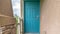 Pano Close up of home entrance with blue green front door and concrete exterior wall