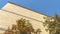 Pano Close up of sunlit building exterior with trees against cloudless blue sky