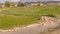 Pano Damaged curving road amid grassy terrain against homes and snow capped mountain