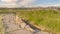 Pano Damaged road with view of homes and snow capped mountain against cloudy sky