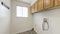 Pano Empty laundry room with top wooden wall cabinet and windows