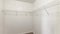Pano Empty storage room with wall mounted white metal shelves and hooks