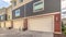 Pano Exterior of three storey townhomes with garages and red gray and beige walls