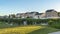 Pano frame Pathway and bridge over pond at a park with lush grasses against houses and sky