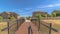 Pano frame Sunny day view of bridge with brown deck and metal handrails over grassy terrain