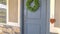 Pano Home exetrior with close up on blue gray front door decorated with green wreath