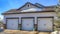 Pano Home with three white hinged garage doors and snowy roof and yard at the facade