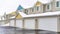 Pano Homes with white garage doors along wet and snowy road on a cloudy winter day