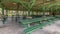 Pano Interior of pavilion with green picnic tables and seats at a park on a sunny day