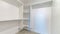 Pano Interior of a walk in closet with shelves and clothes rod mounted on white wall