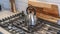 Pano Kettle on top of a cooktop against wooden chopping board and tile backsplash