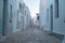 Pano Koufonisi island, Greece. Stonewall building, empty cobblestone street, blue sky background