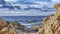 Pano Laguna Beach California shore with rocks and sand against ocean and cloudy sky