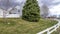 Pano Landscaped yard of house with low fence along road with cloudy sky bakcground