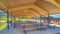 Pano Park pavilion playground and basketball court gainst homes mountain and blue sky