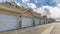 Pano Road along white doors of attached garages of townhouses on a sunny day