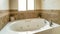 Pano Round white built in bathtub against warm toned tiles and plain beige wall