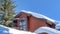 Pano Snowy home exterior and evergreen tree against blue sky on a sunny winter day