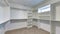 Pano Walk in closet of house with empty built in shelves and two levels clothing rods