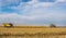 Panoram of corn field where harvesters are working, beautiful sky