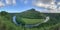 Panorama Aerial scene view of a mountain river with a boat sailing round high round mountain covered with trees on the horizon.