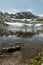 Panorama of alpine lake with melting ice and mountains