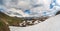 Panorama of alpine valley and mountains in spring with snowfield