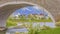 Panorama Arched bridge over a glistening lake with a view of homes and snowy mountain