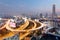 Panorama of Bangkok at dusk with skyscrapers in background and traffic trails on elevated expressways and circular interchanges