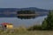 Panorama of Batak dam reservoir with island in the water and coastal autumn glade, cottage, forest, hill at Rhodope mountains