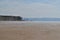 Panorama of a beach in the morning haze against the background of the silhouette of a mountains on the opposite bank of the river.