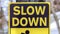 Panorama Black and yellow Slow Down Kids And Pets At Play sign against gray wooden pole