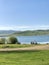 Panorama of a blue lake in the Ural mountains with people sitting on the promenade on the shore