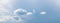 Panorama of blue sky with sunlit small white clouds