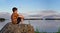 Panorama of a boy sitting on rock in summer evening sunlight