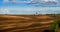 Panorama of brown arable land over amazing clouds