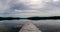 Panorama of a calm lake with reflections of mountains and sky and a wooden dock in the foreground