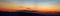 Panorama of the Carpathian mountains at sunset and the lights of the village in the haze