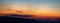 Panorama of the Carpathian mountains at sunset and the lights of the village in the haze