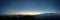 Panorama of the Carpathian mountains at sunset and the lights of the village in the haze, rest and travel in the mountains