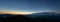 Panorama of the Carpathian mountains at sunset and the lights of the village in the haze, rest and travel in the mountains