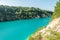 Panorama of chalkpit on limestone coast of huge turquoise lake or river near forest. Chalk quarry filled with water