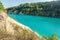 Panorama of chalkpit on limestone coast of huge turquoise lake or river near forest. Chalk quarry filled with water