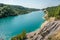 Panorama of chalkpit on limestone coast of huge turquoise lake or river near forest. Chalk quarry filled with water