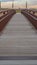 Panorama Close up of a bridge with a wooden deck and brown metal guardrails